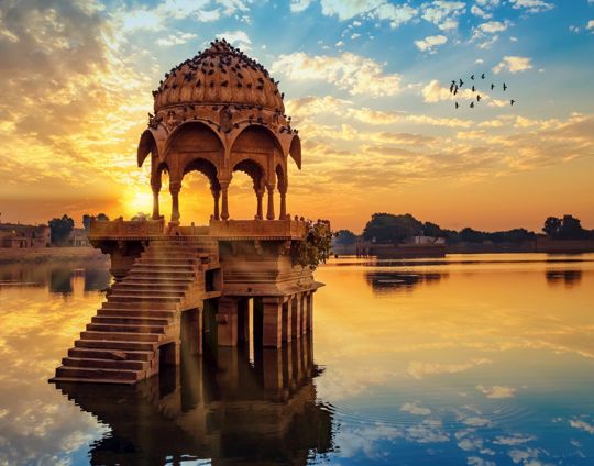 Ancient Architecture Ruins At Gadi Sagar (Gadisar) Lake Jaipur Rajasthan At Sunrise With Vibrant Moody Sky.